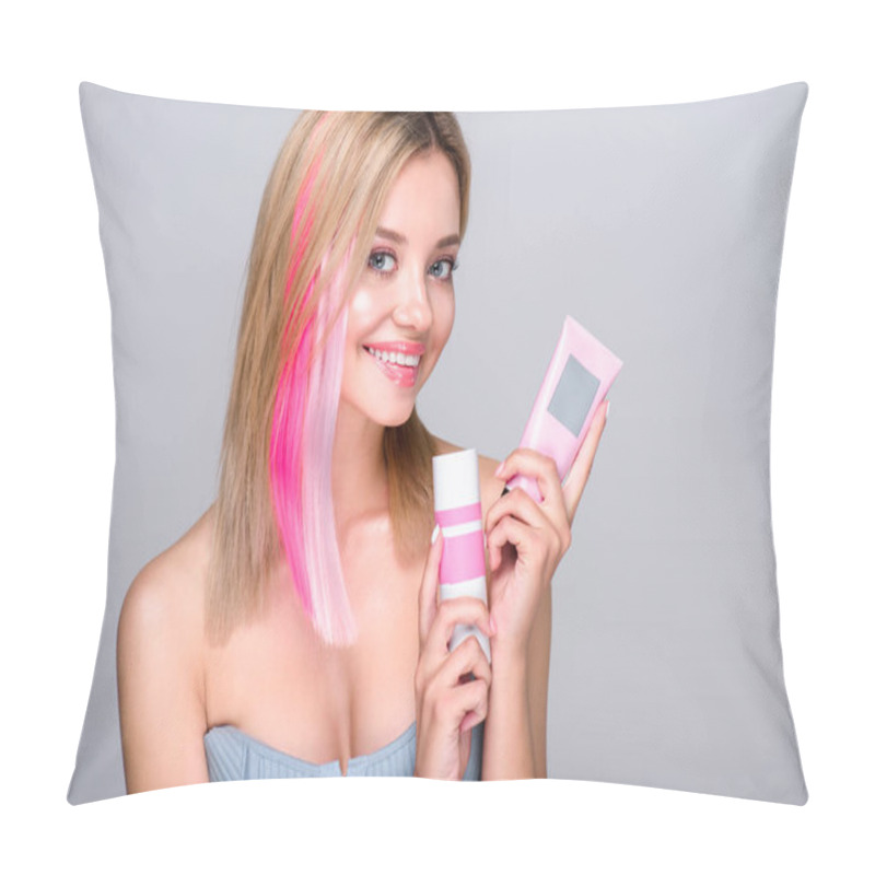 Personality  smiling young woman with colored bob cut holding hair care supplies and looking at camera isolated on grey pillow covers