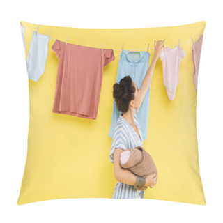 Personality  Brunette Woman Hanging Clothing On Rope While Holding Baby Doll On Yellow Background Pillow Covers