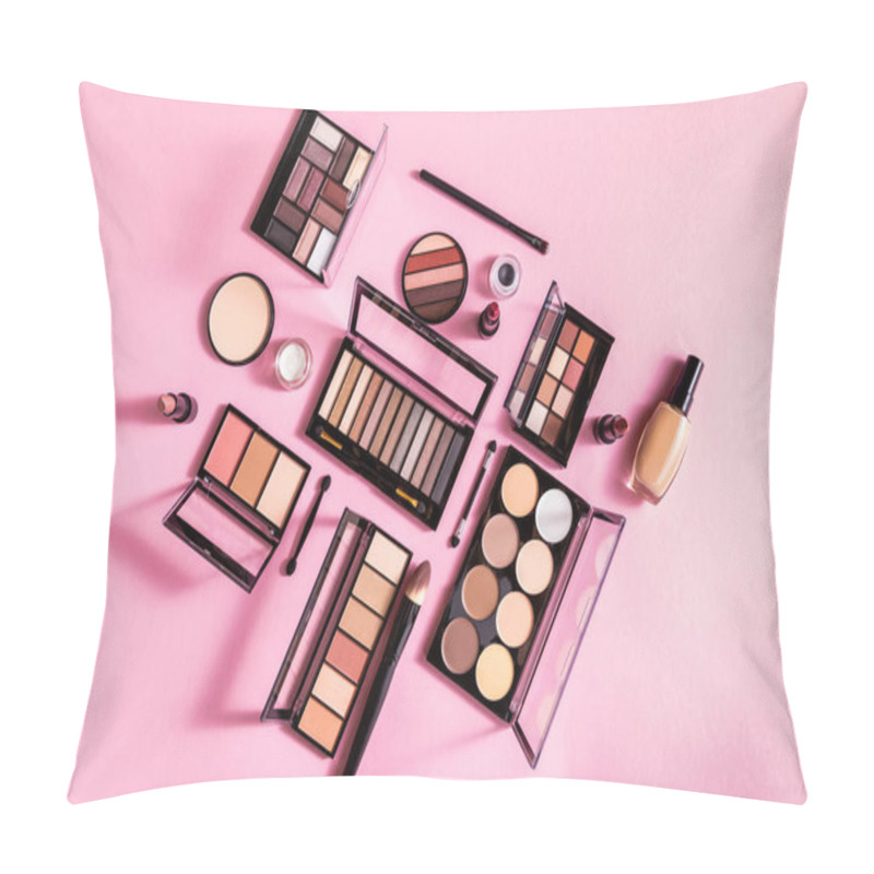Personality  top view of eye shadow and blush palettes near face powder, cosmetic brushes, lipsticks and face foundation on pink pillow covers