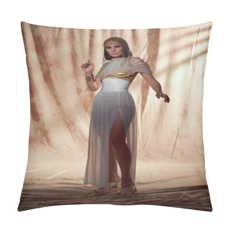 Personality  Trendy model in egyptian attire and pearl top posing while standing on abstract background pillow covers