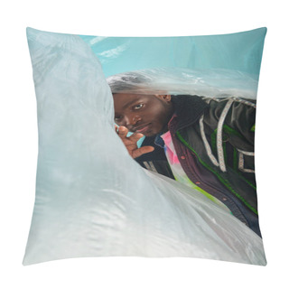 Personality  Fashionable Young African American Man In Outwear Jacket With Led Stripes Standing Near Glossy Cellophane On Turquoise Background, Urban Outfit And Modern Pose, Creative Expression, DIY Clothing  Pillow Covers