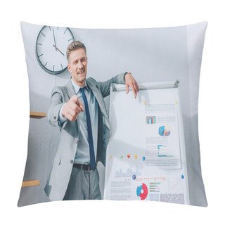 Personality  Cheerful Businessman Pointing At Camera While Standing Near Flipchart With Graphs  Pillow Covers