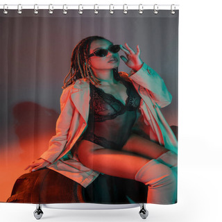 Personality  Glamorous And Sassy African American Woman Adjusting Dark Stylish Sunglasses While Sitting On Huge Tire In Black Lace Bodysuit And Beige Coat On Grey Background With Red Lighting Shower Curtains
