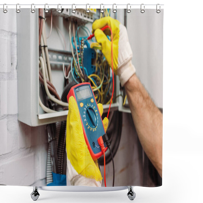 Personality  Cropped view of workman in gloves using multimeter while checking voltage of electric panel shower curtains