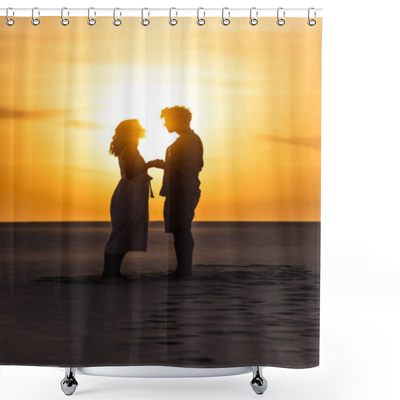 Personality  side view of silhouettes of man and woman holding hands on beach against sun during sunset shower curtains