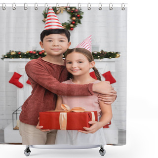 Personality  Asian Boy Hugging Friend In Party Cap Holding Gift Box Near Blurred Christmas Decor At Home  Shower Curtains