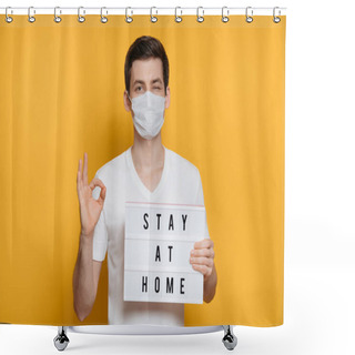 Personality  Young Man In Medical Mask Winking One Eye While Showing OK Gesture And Holding Board With Stay At Home Text. Coronavirus Or COVID-19 Pandemic And Quarantine Concept. Isolated On Yellow Background Shower Curtains