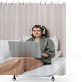 Personality  Young Woman With Wavy Brunette Hair, In Casual Clothes And Wireless Headphones Sitting On Bed Near White Pillows And Smiling While Watching Film On Laptop In Hotel Room  Shower Curtains