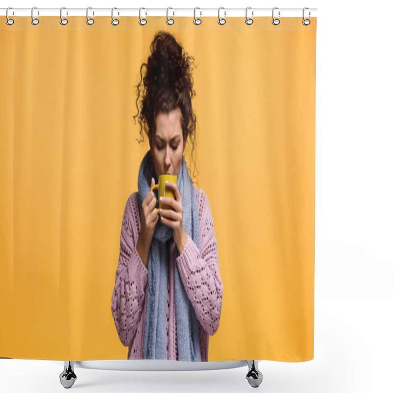 Personality  young woman in sweater and scarf drinking warm tea isolated on orange shower curtains