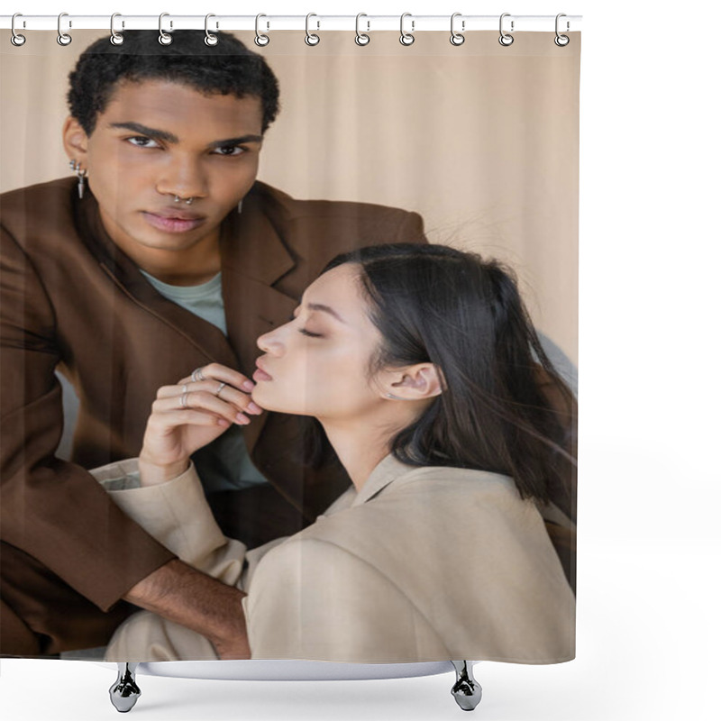Personality  stylish african american guy with piercing looking at camera near young asian woman with closed eyes isolated on beige shower curtains