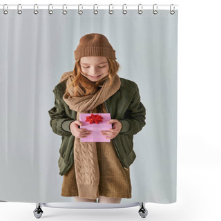 Personality  Happy Preteen Kid In Stylish Outfit With Winter Hat Holding Christmas Present And Standing On Grey Shower Curtains