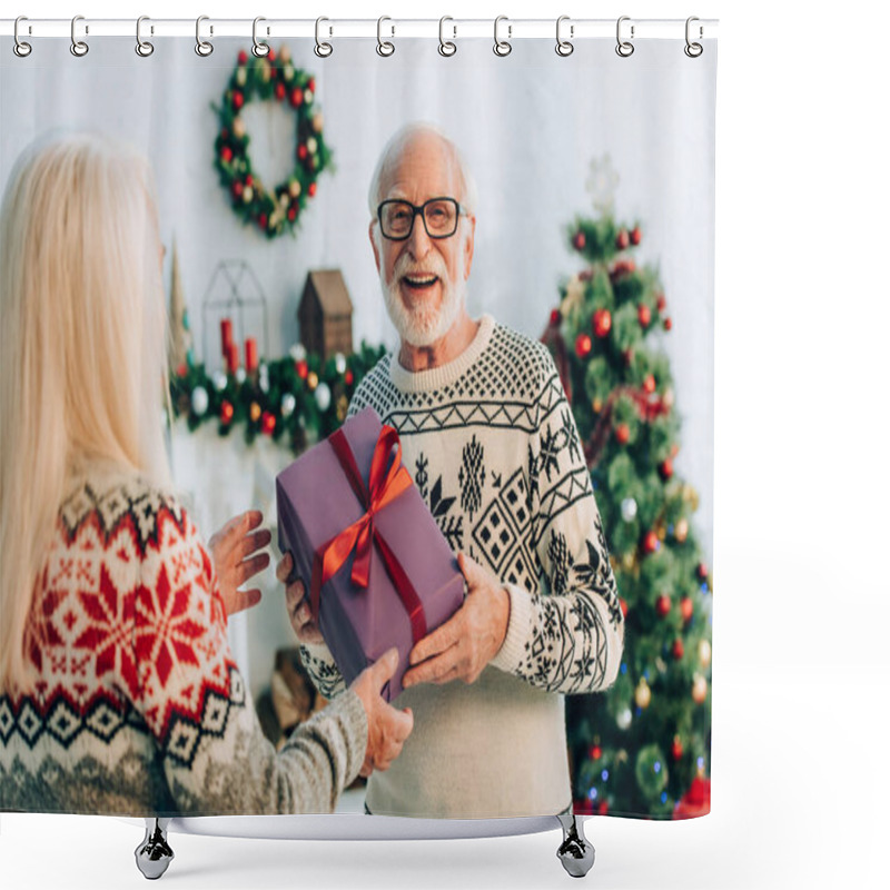 Personality  selective focus of happy senior man looking at camera while presenting christmas gift to wife shower curtains