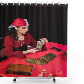 Personality  KYIV, UKRAINE - FEBRUARY 23, 2022: Young Gypsy Fortune Teller Holding Tarot Card Near Jars And Book Isolated On Black  Shower Curtains