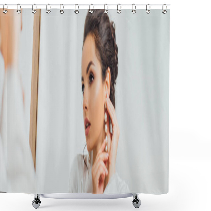 Personality  Panoramic shot of bride in silk robe putting on pearl earring near mirror  shower curtains