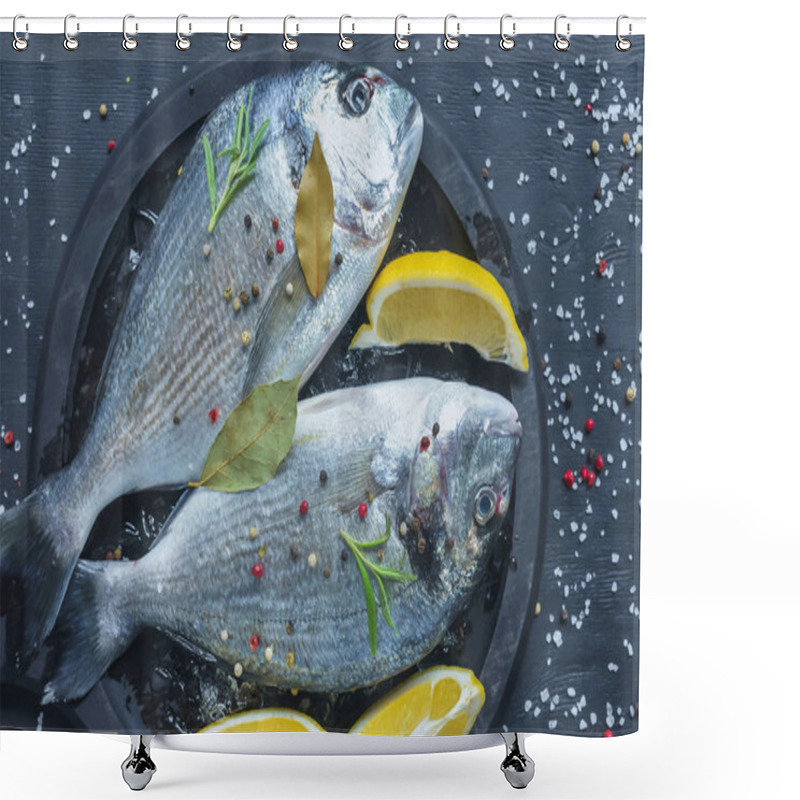 Personality  flat lay with raw fish with lemon, bay leaves and rosemary in tray on black table covered by salt and pepper shower curtains