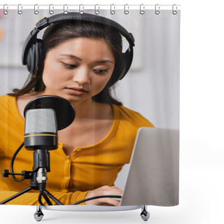 Personality  Selective Focus Of Concentrated Asian Broadcaster In Wireless Headphones Using Laptop Near Microphone Shower Curtains