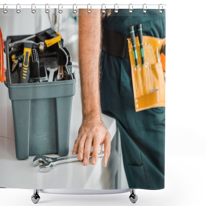 Personality  cropped image of plumber leaning on kitchen counter and touching adjustable wrench in kitchen shower curtains