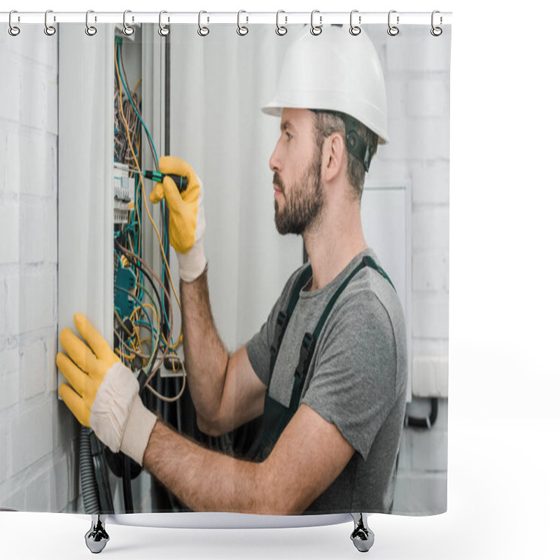 Personality  side view of handsome bearded electrician repairing electrical box and using screwdriver in corridor shower curtains