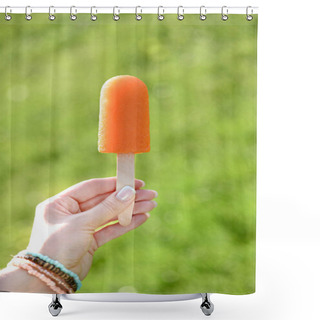 Personality  Hand Holding Orange Popsicle On Blurred Green Background Shower Curtains