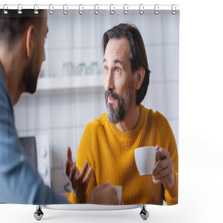 Personality  Bearded Man Holding Coffee Cup And Gesturing While Talking To Son In Kitchen, Blurred Foreground Shower Curtains