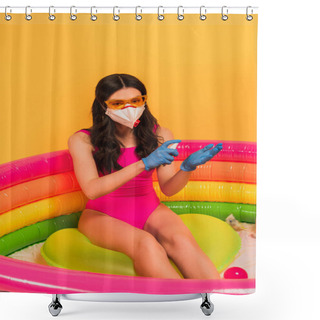 Personality  Young Woman In Swimsuit, Sunglasses, Latex Gloves And Medical Mask Sitting In Inflatable Pool And Applying Sanitizer On Yellow Shower Curtains