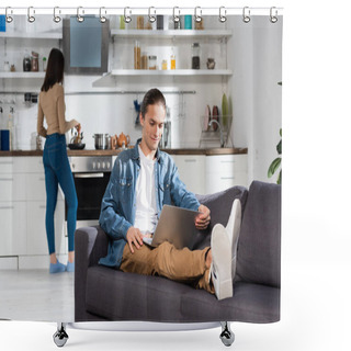 Personality  Selective Focus Of Man Using Laptop On Sofa In Kitchen And Woman Standing On Background Shower Curtains