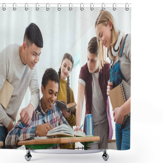 Personality  Smiling African American Schoolboy Writing In Notebook While His Classmates Standing Around Shower Curtains