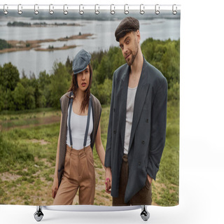 Personality  Confident And Bearded Man In Jacket Holding Hand Of Fashionable Girlfriend In Newsboy Cap And Suspenders And Looking At Camera While Standing With Nature At Background, Stylish Pair Amidst Nature Shower Curtains