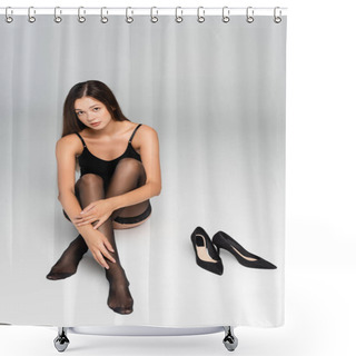 Personality  Sexy Young Adult Woman With Crossed Legs, Looking At Camera, While Sitting Near Black Shoes On Grey Shower Curtains