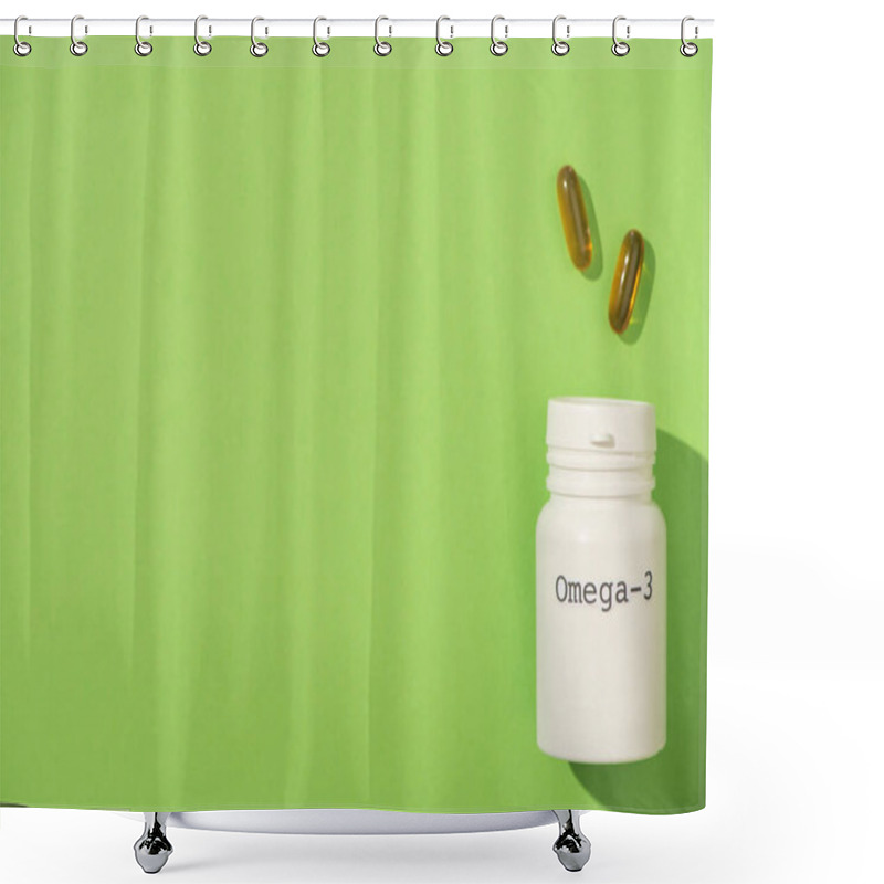 Personality  Top view of container with omega-3 lettering near capsules on green shower curtains