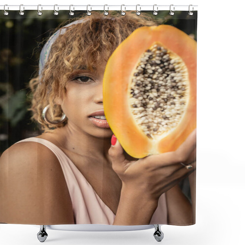 Personality  Portrait of young and fashionable african american woman in headscarf and summer dress holding cut and ripe papaya and covering face near plants, stylish lady blending fashion and nature shower curtains