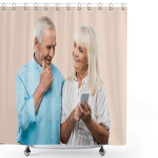 Personality  Cheerful Retired Woman Holding Smartphone And Looking At Husband Isolated On Beige  Shower Curtains