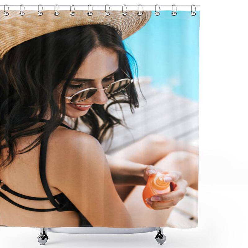 Personality  high angle view of smiling brunette woman in sunglasses and straw hat applying sunscreen at poolside shower curtains