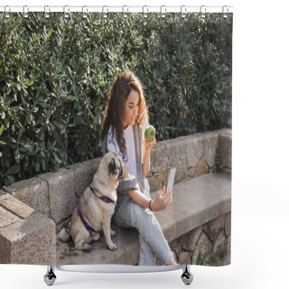 Personality  Smiling And Curly Young Woman In Casual Clothes Using Mobile Phone And Wired Earphones While Holding Fresh Apple Near Pug Dog On Stone Bench In Park In Barcelona, Spain  Shower Curtains