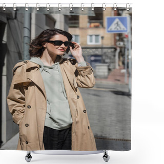Personality  Young Appealing Woman With Wavy Brunette Hair Adjusting Dark Stylish Sunglasses While Standing In Grey Hoodie And Beige Trench Coat In City On Blurred Background, Street Photography Shower Curtains