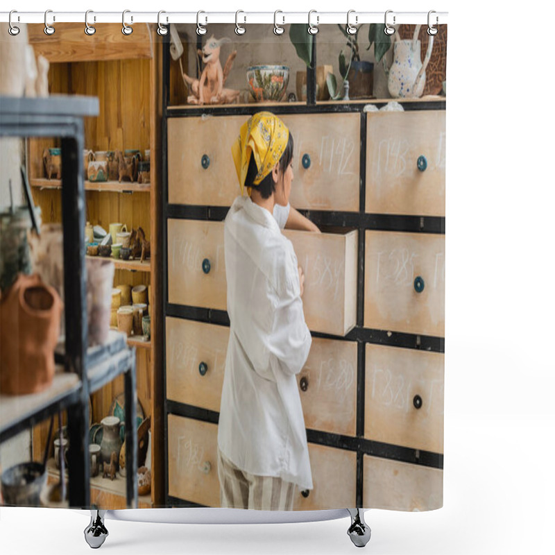 Personality  Side View Of Young Brunette Asian Craftswoman In Headscarf And Workwear Opening Cupboard While Standing And Working In Ceramic Studio, Pottery Workshop With Skilled Artisan Shower Curtains