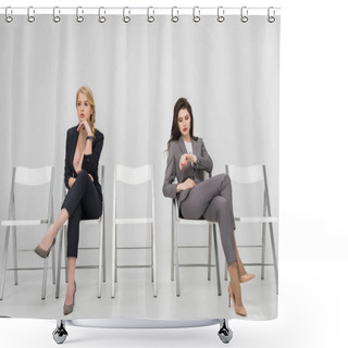 Personality  Businesswoman Sitting With Crossed Legs And Looking At Watch Near Pensive Female Coworker Isolated On Grey Shower Curtains