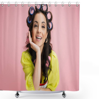 Personality  Portrait Of Brunette Woman In Yellow Blouse And Hair Curlers Holding Hand Near Face And Looking At Camera Isolated On Pink Shower Curtains