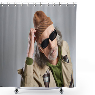 Personality  Portrait Of Thoughtful Elderly Man In Dark Sunglasses And Beige Trench Coat Touching Beanie Hat And Looking At Camera On Grey Background, Hipster Fashion, Stylish And Positive Aging Concept Shower Curtains