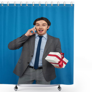 Personality  Young Man In Fashionable Suit Holding Gift Box With Red Ribbon And Speaking On Cellphone Isolated On Blue Shower Curtains