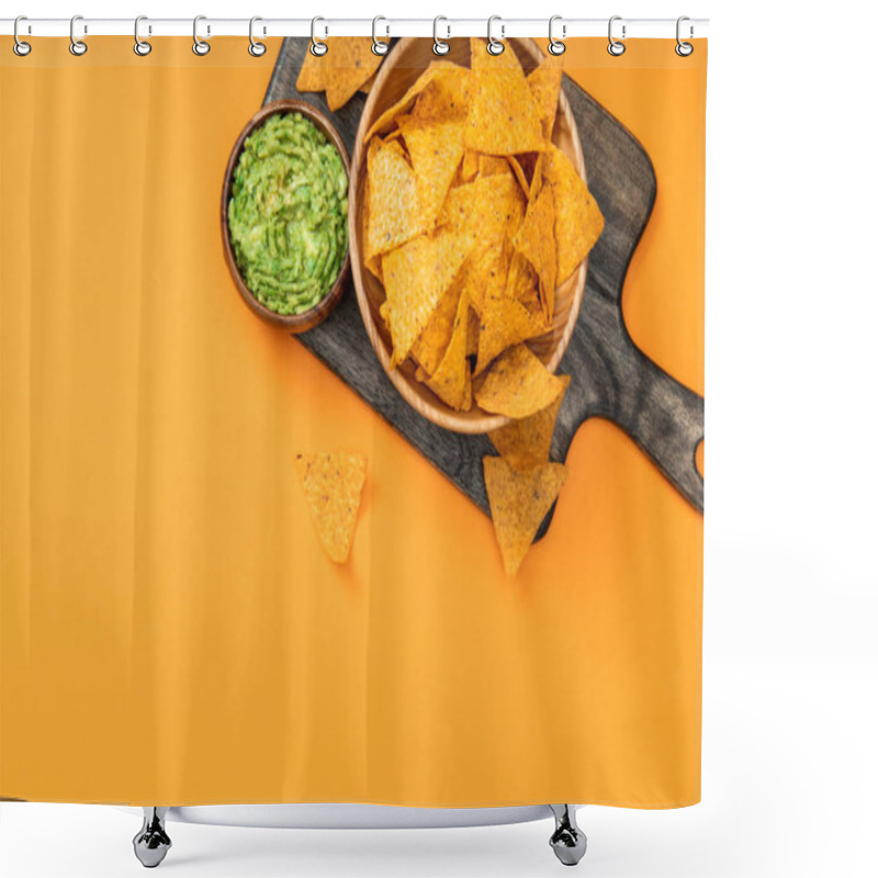 Personality  top view of crispy Mexican nachos served with guacamole on wooden cutting board on orange background shower curtains