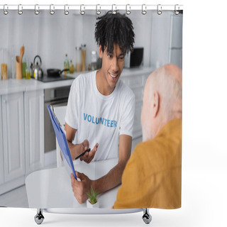Personality  Cheerful African American Volunteer Pointing At Clipboard Near Blurred Senior Man In Kitchen  Shower Curtains