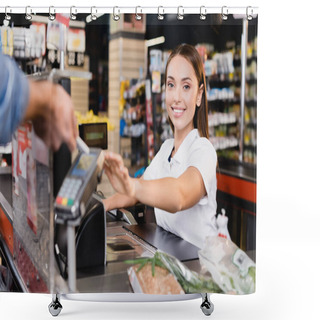 Personality  Smiling Cashier Looking At Camera Near Customer Paying With Smartphone On Blurred Foreground In Supermarket  Shower Curtains