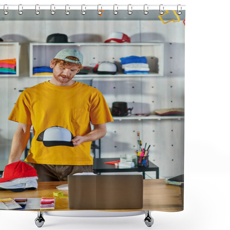Personality  Young Redhead Craftsman Holding Snapback While Working On Project Near Laptop And Cloth Samples On Table And Standing In Blurred Print Studio, Small Business Resilience Concept Shower Curtains