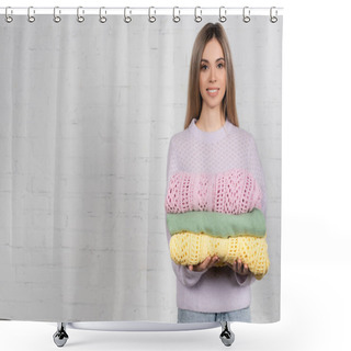 Personality  Young Woman Smiling At Camera While Holding Colorful Sweaters With White Brick Wall At Background Shower Curtains