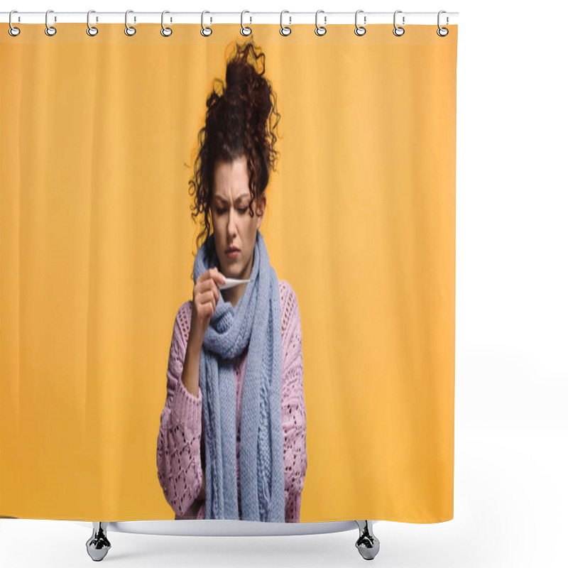 Personality  displeased woman in knitted sweater and scarf looking at thermometer isolated on orange shower curtains