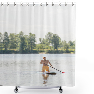 Personality  Young And Active Man In Yellow Swim Shorts Holding Paddle And Kneeling On Sup Board While Sailing On Scenic River With Green Trees On Bank With Picturesque Riverside On Background Shower Curtains