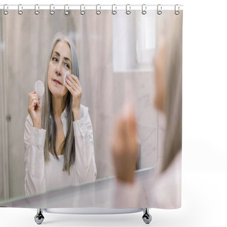 Personality  Skin Care And Hygiene Concept. Charming Senior Gray Haired Lady Using A Cotton Pad With Micellar Water For Removing Make Up From Face, Standing In Bathroom And Looking In The Mirror Shower Curtains