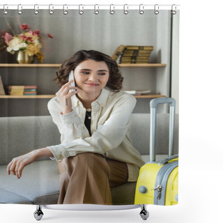 Personality  Happy Young Woman With Wavy Brunette Hair And Tattoo Sitting On Couch And Talking On Mobile Phone Near Yellow Travel Bag, Books And Vase With Flowers On Shelves In Hotel Lobby On Blurred Background Shower Curtains