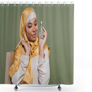 Personality  Smiling Multiracial Woman In Hijab Holding Shopping Bag And Serum Isolated On Green  Shower Curtains